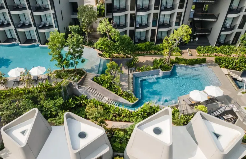 Vue aérienne d'un complexe hôtelier avec piscine et végétation luxuriante.