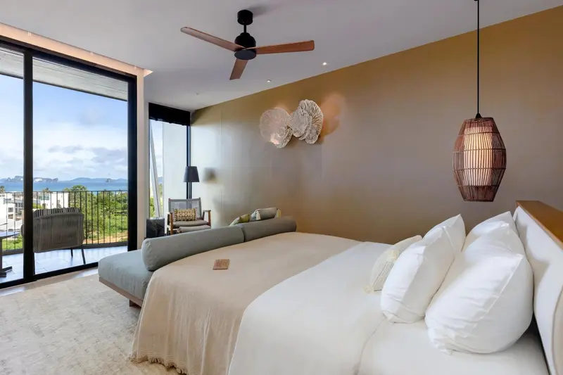 Une chambre lumineuse avec un grand lit et un accès à une terrasse offrant une vue sur la mer.
