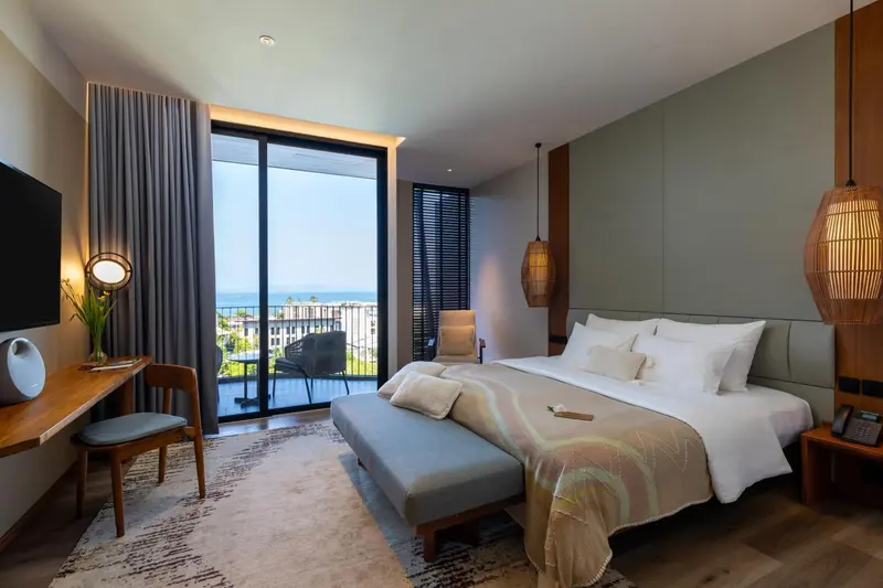Chambre lumineuse avec un grand lit et une vue sur la mer.