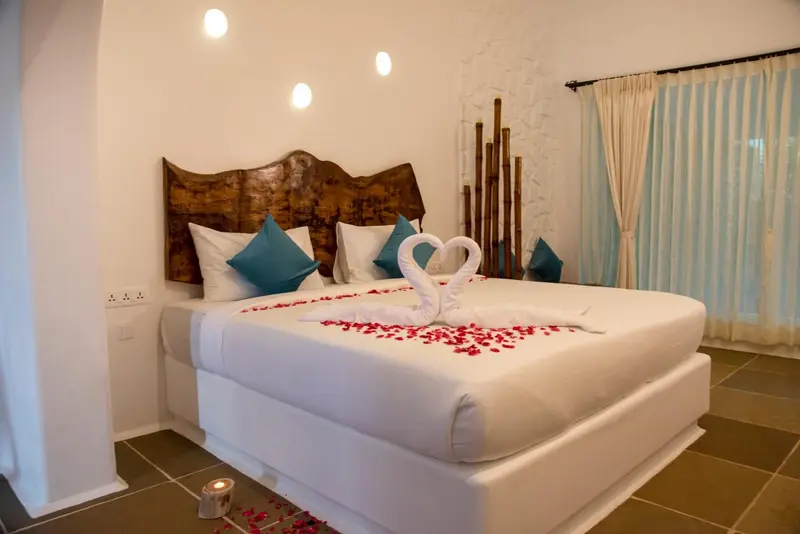 Une chambre lumineuse avec un grand lit décoré de pétales de fleurs.