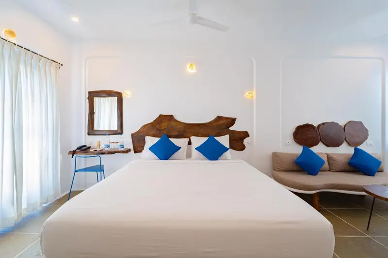 Une chambre lumineuse avec un grand lit et un coin salon.