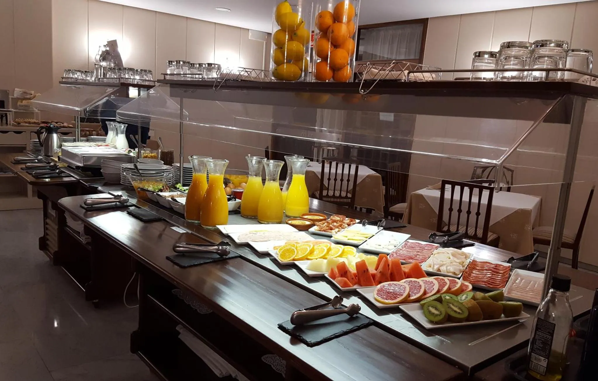 Un buffet propose des fruits, des viennoiseries et des boissons.