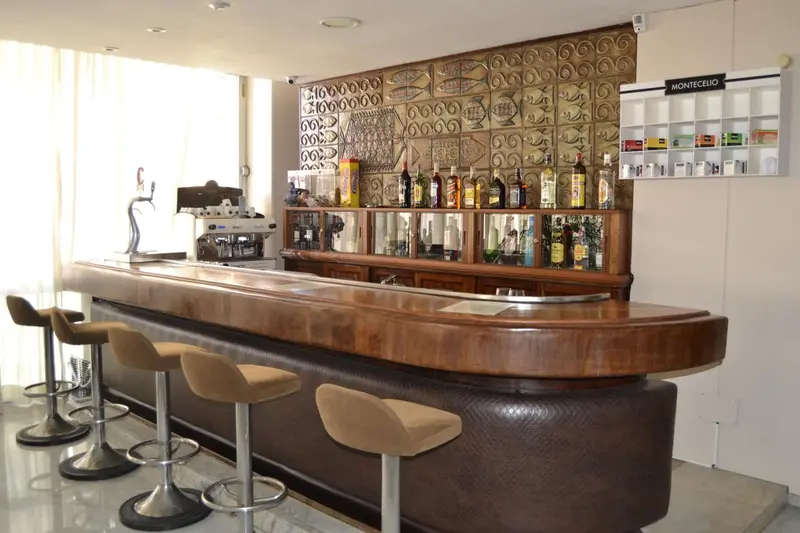 Un comptoir de bar en bois avec des tabourets est présenté dans une pièce lumineuse.