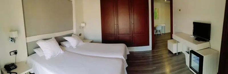 Une chambre lumineuse avec un grand lit et un meuble télévision.