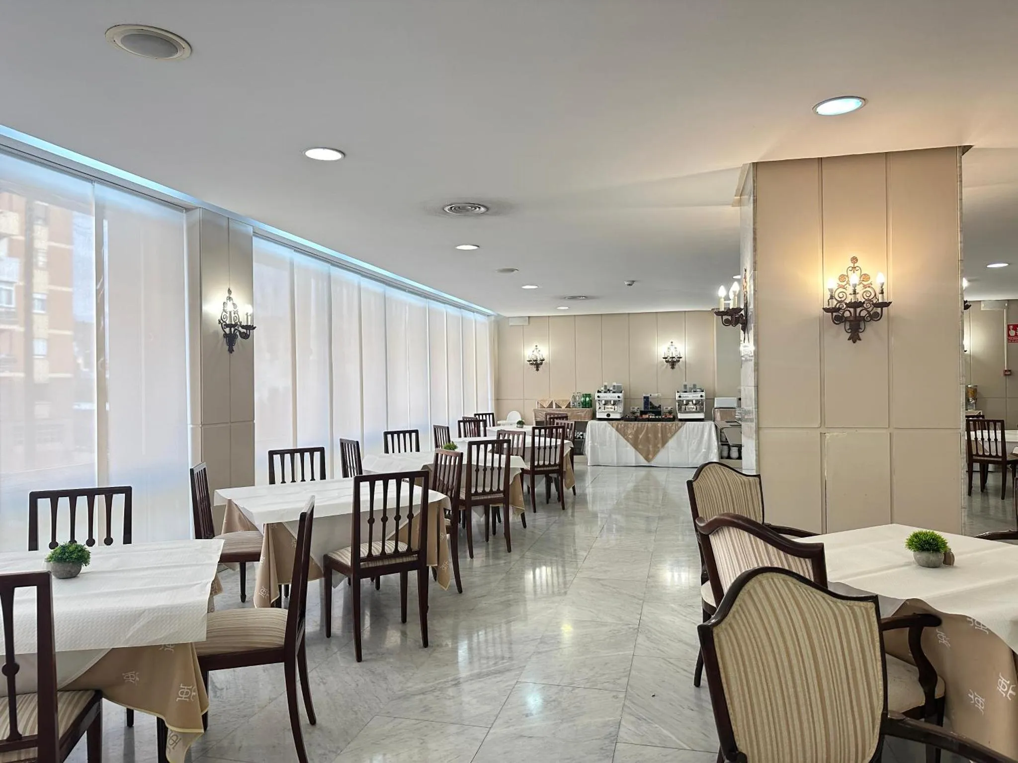 Une salle lumineuse avec des tables dressées pour un repas.