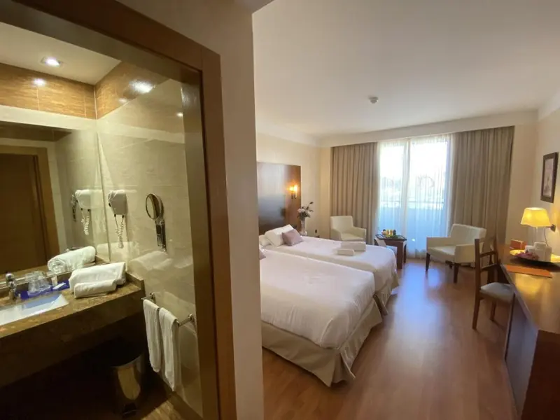 Chambre lumineuse avec deux lits simples et salle de bain attenante.