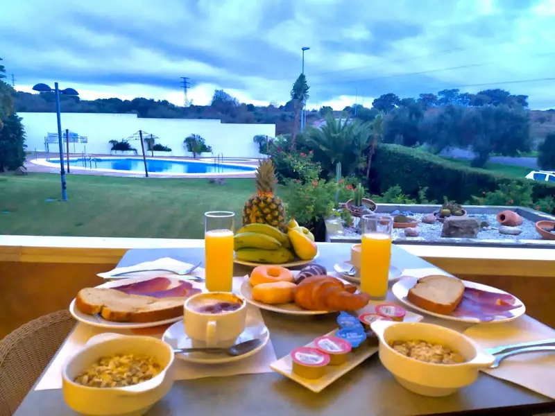 Table de petit-déjeuner avec vue sur une piscine et un jardin verdoyant.