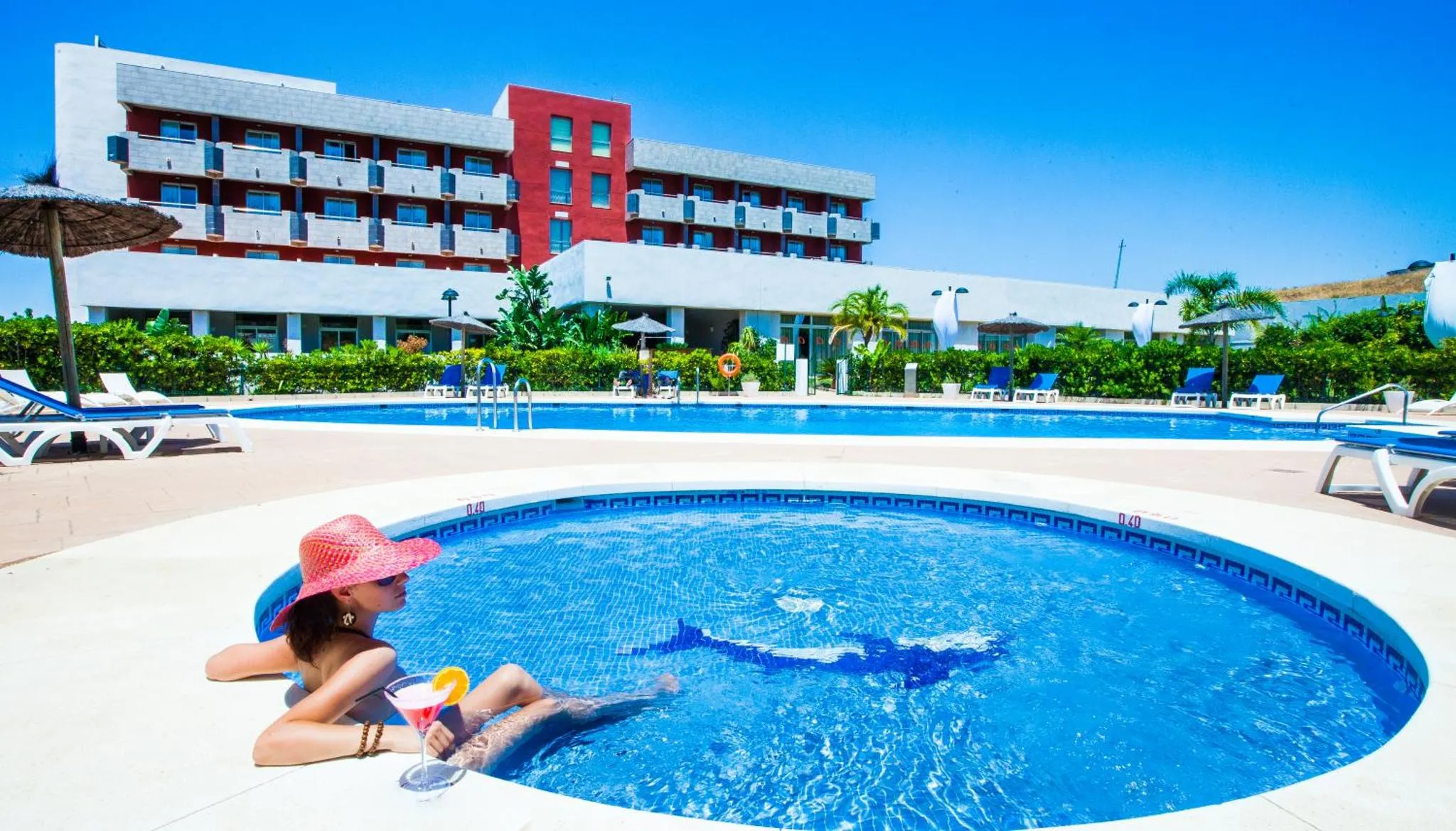 Une femme se détend dans un jacuzzi au bord d'une piscine d'hôtel.