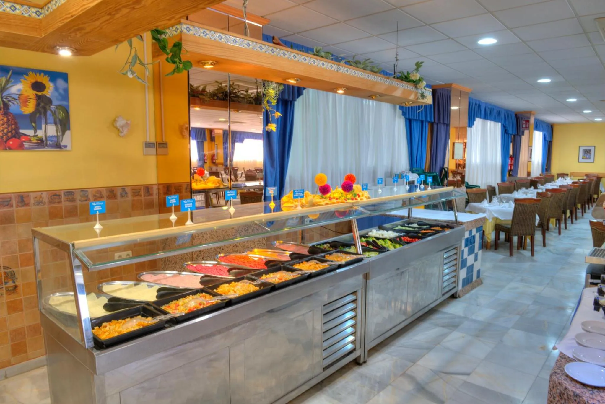Un buffet propose une variété de salades et de plats froids dans une salle lumineuse.