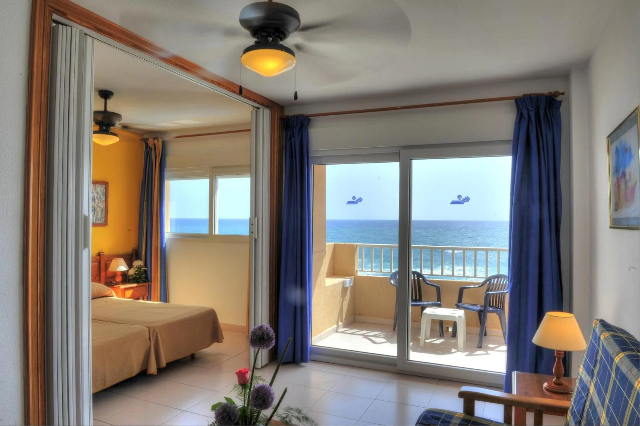 Une chambre lumineuse s'ouvre sur une terrasse avec vue sur la mer.