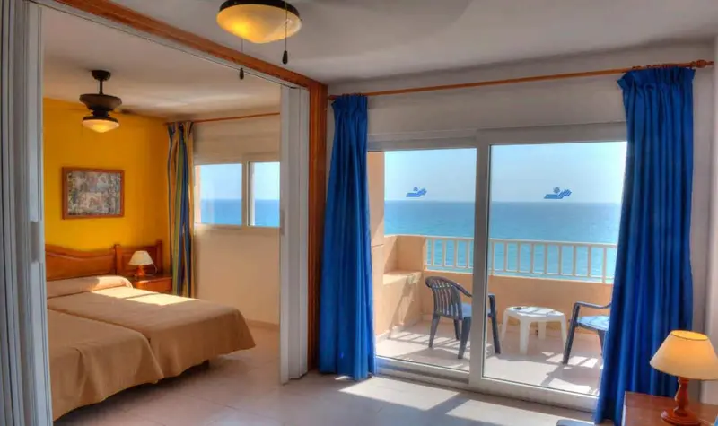 Une vue d'ensemble d'une chambre d'hôtel avec un lit double, un ventilateur de plafond et un ventilateur de plafond
