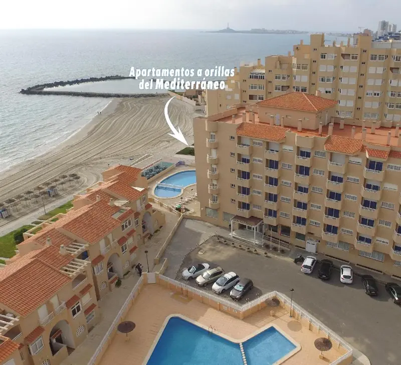 Vue aérienne d'un complexe hôtelier avec piscine et accès à la plage.