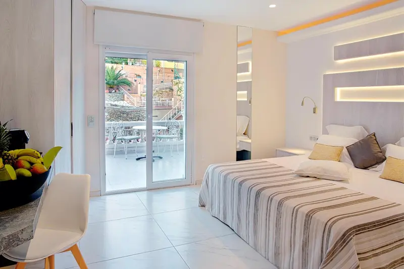 Une chambre lumineuse avec un lit et un accès à une terrasse.