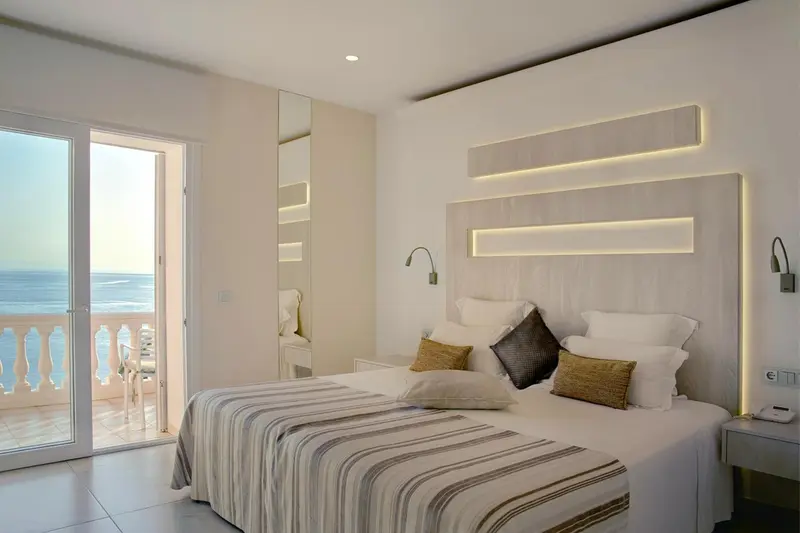 Une chambre lumineuse avec un grand lit et une vue sur la mer.