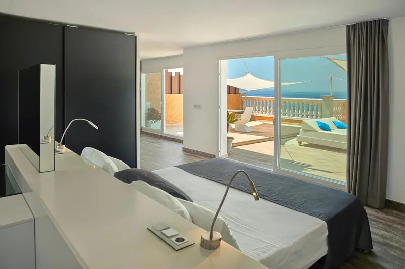 Une chambre moderne avec un grand lit et un accès direct à une terrasse ensoleillée.