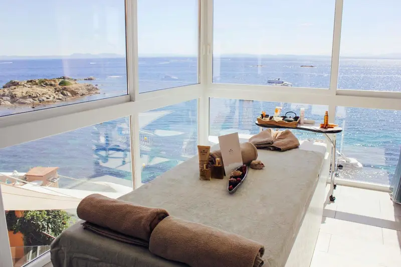 Une table de massage est mise en place devant une grande baie vitrée donnant sur la mer.