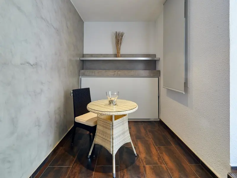 Une petite table ronde et une chaise en osier se trouvent dans un coin de pièce.