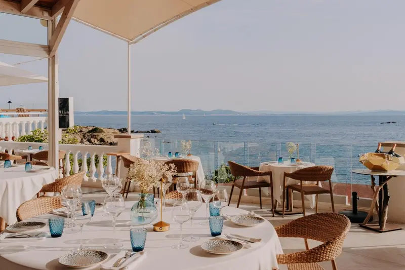 Tables dressées en terrasse avec vue sur la mer.
