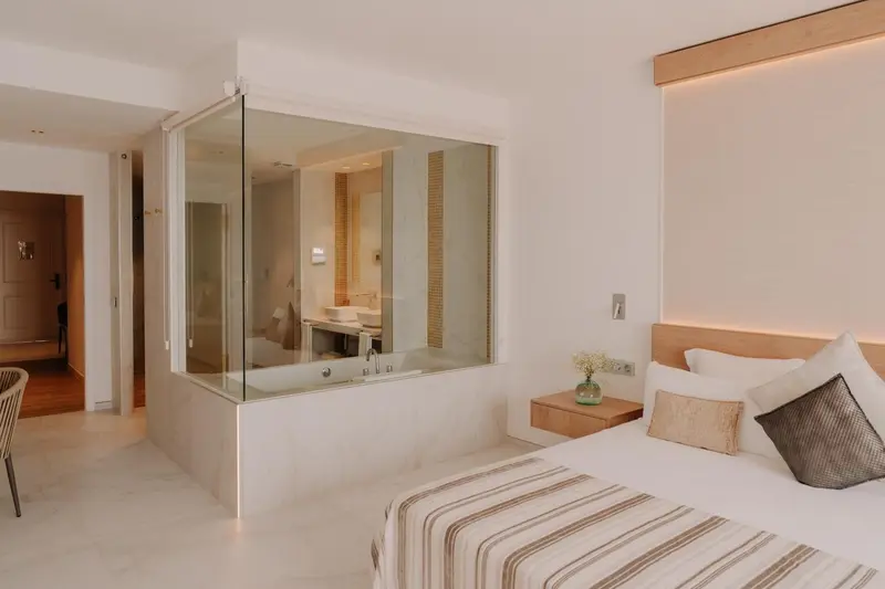 Chambre lumineuse avec un grand lit et une salle de bain attenante.