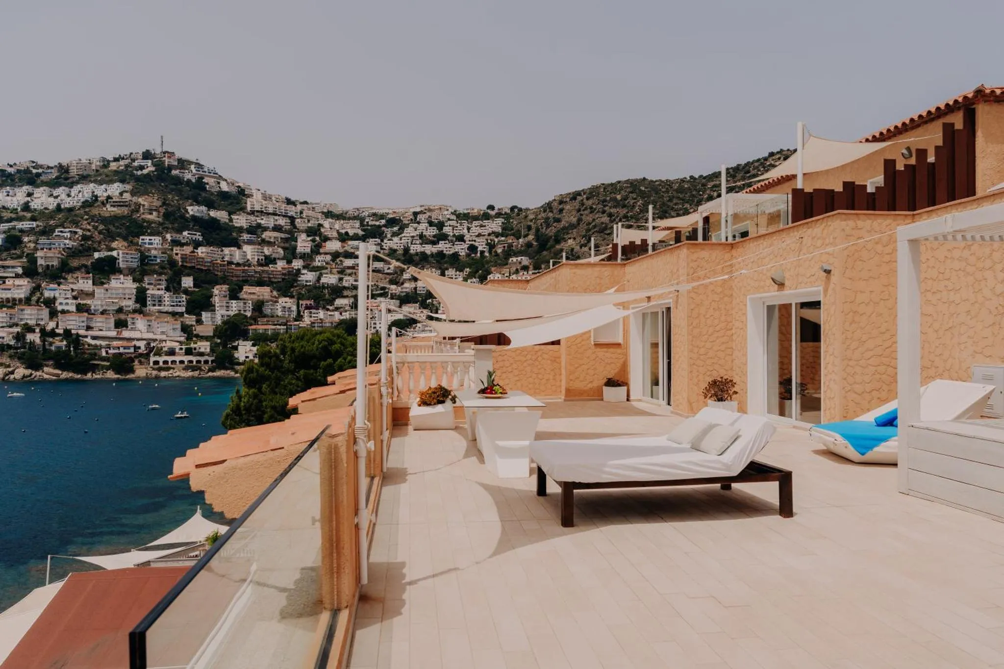 Terrasse avec mobilier de détente et vue sur la mer et les collines.
