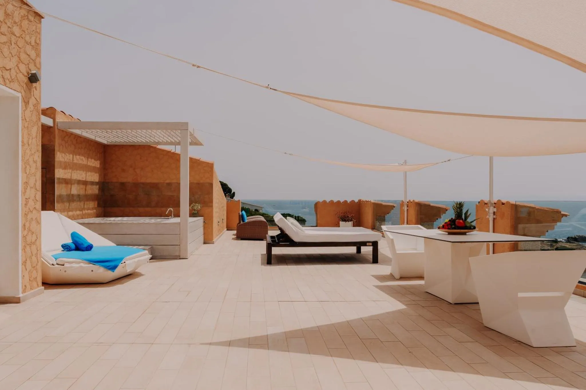 Terrasse aménagée avec transats et table basse, vue sur la mer.
