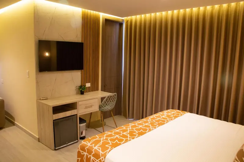 Une chambre lumineuse avec un bureau et un lit recouvert d'une courtepointe.