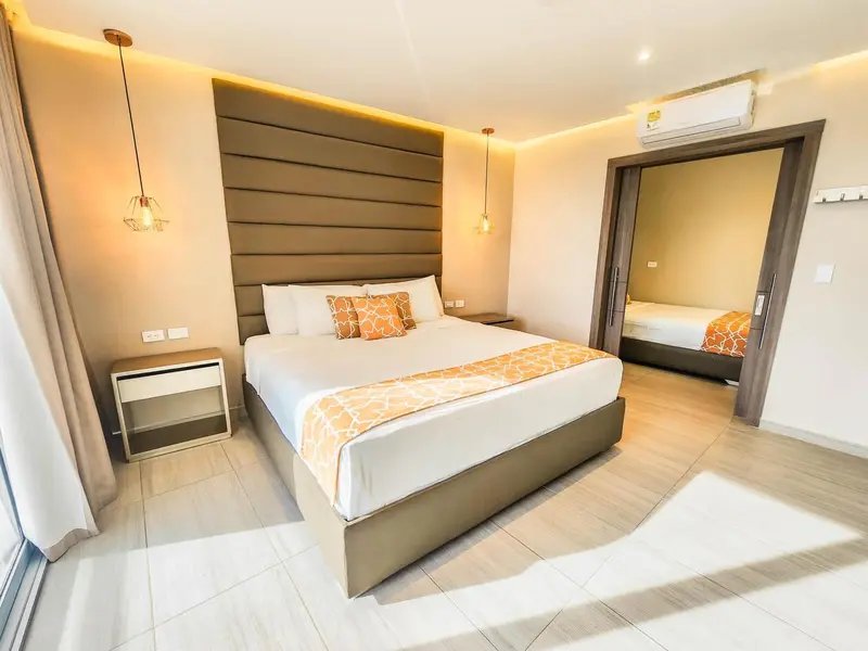 Une chambre lumineuse avec un grand lit et un espace nuit séparé.