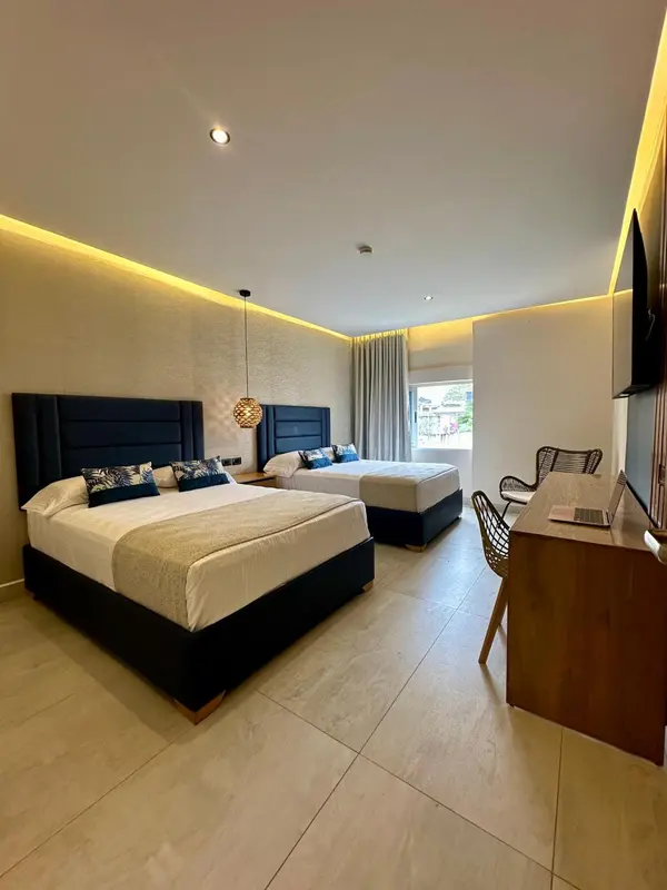 Chambre lumineuse avec deux lits et un espace bureau.