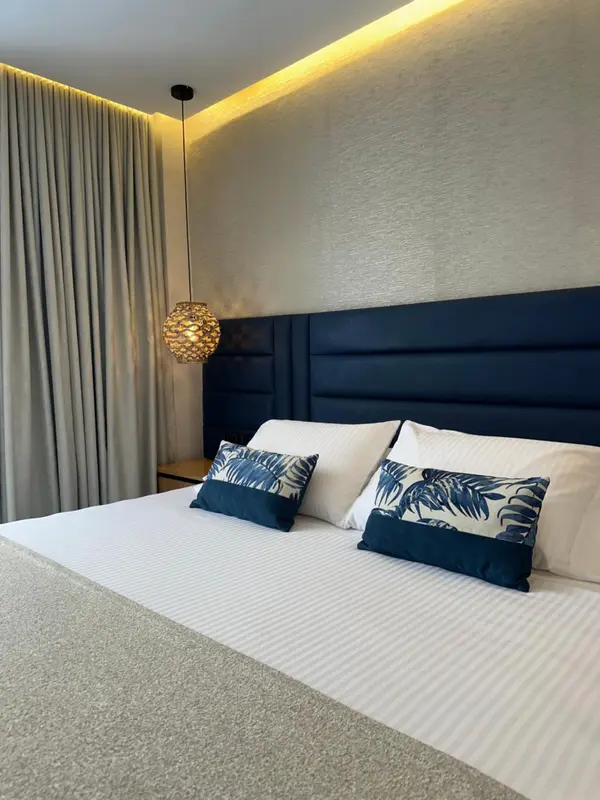 Un lit double est fait dans une chambre décorée de coussins et de rideaux.