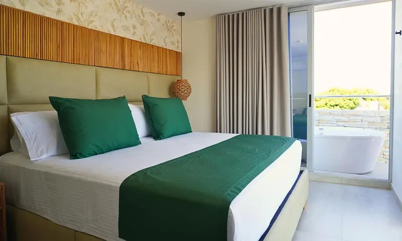 Une chambre lumineuse avec un grand lit et un accès à une terrasse avec jacuzzi.