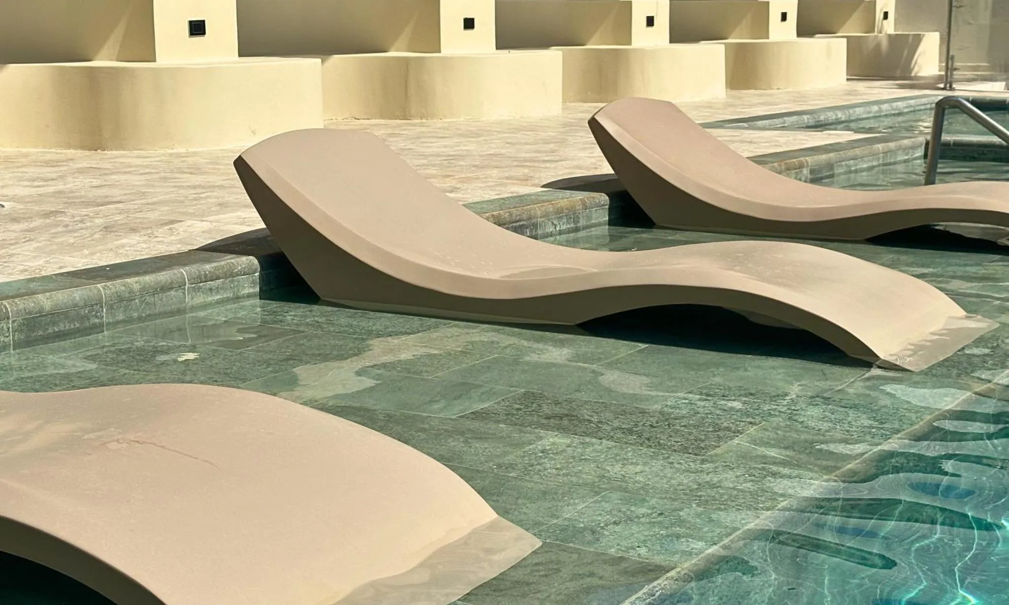 Transats blancs au bord d'une piscine turquoise.