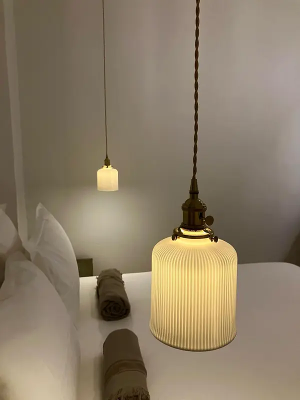 Une lampe suspendue éclaire un lit avec des oreillers et des couvertures.