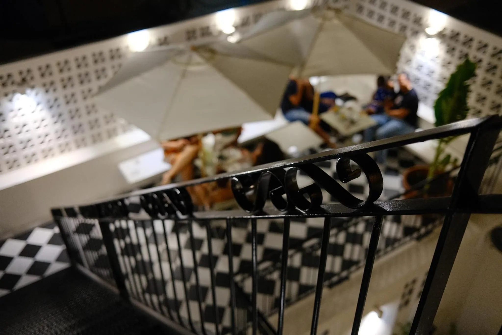 Une terrasse avec des tables et des chaises éclairées par des lampes.