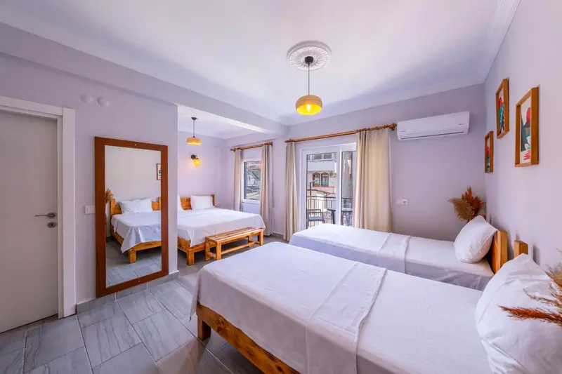 Une chambre lumineuse avec deux lits simples et un lit double.