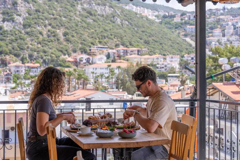 Deux personnes prennent leur petit-déjeuner sur une terrasse avec vue sur la ville.