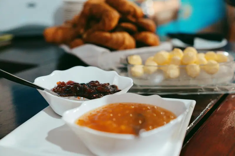 Assortiment de confitures et de viennoiseries présentées sur un buffet.