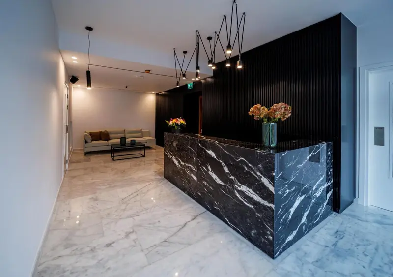 Un comptoir d'accueil moderne avec un mur sombre et des luminaires suspendus.