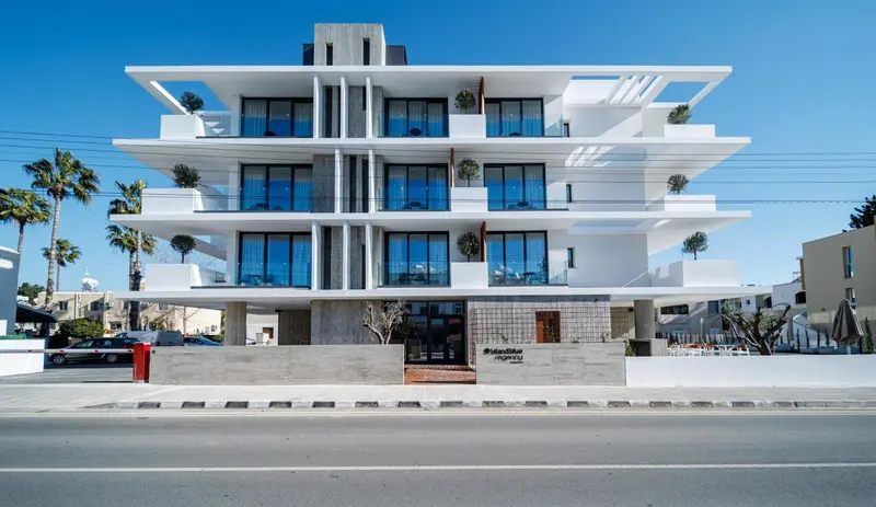 Façade moderne d'un bâtiment blanc à plusieurs étages avec des balcons.