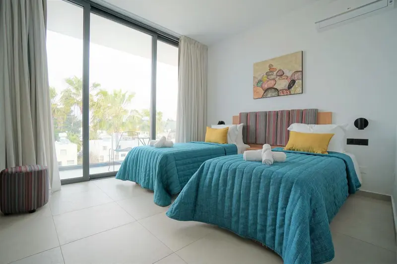 Chambre lumineuse avec deux lits simples et vue sur la mer.