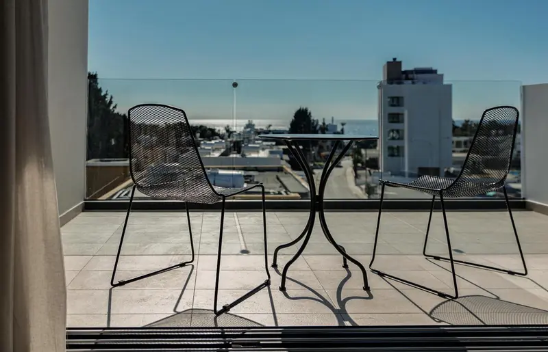 Terrasse avec table et chaises donnant sur une vue urbaine et la mer.