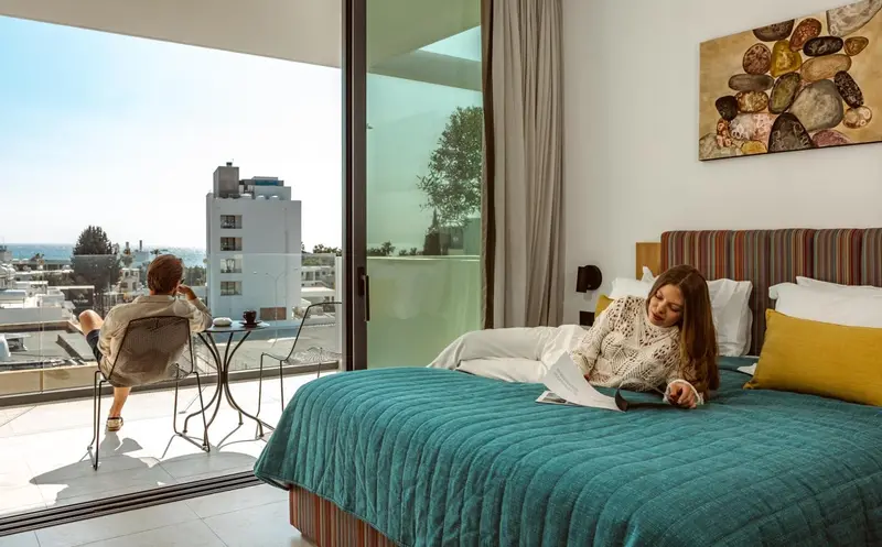 Une chambre lumineuse avec un grand balcon donnant sur la ville.