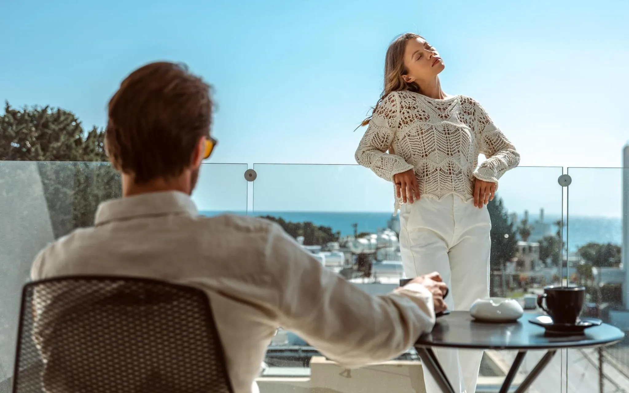 Un couple se tient sur une terrasse avec vue sur la mer.