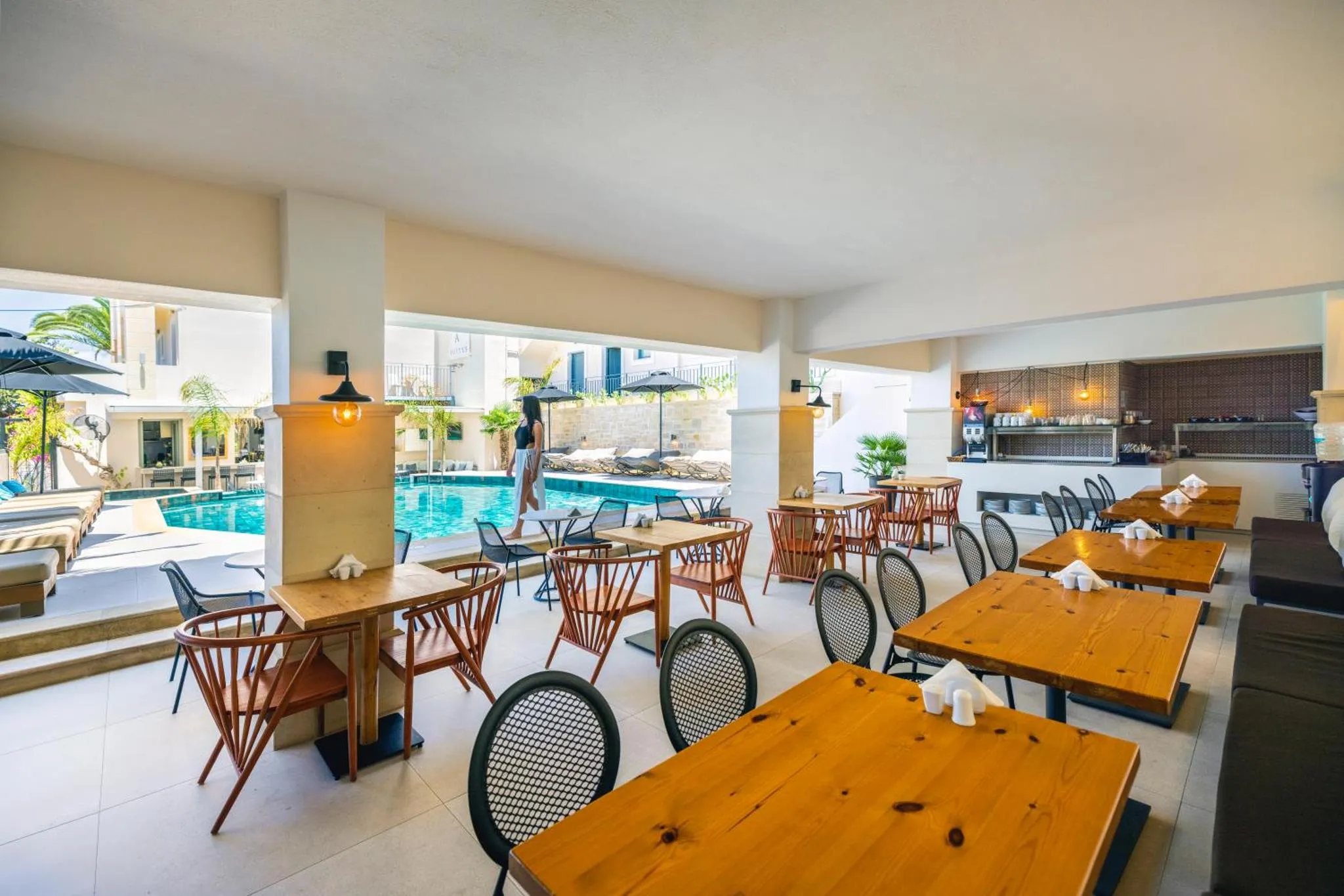Une salle lumineuse avec des tables et des chaises en bois, donnant sur une piscine et un espace extérieur.