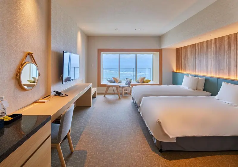 Une chambre lumineuse avec deux lits et une vue sur la mer.