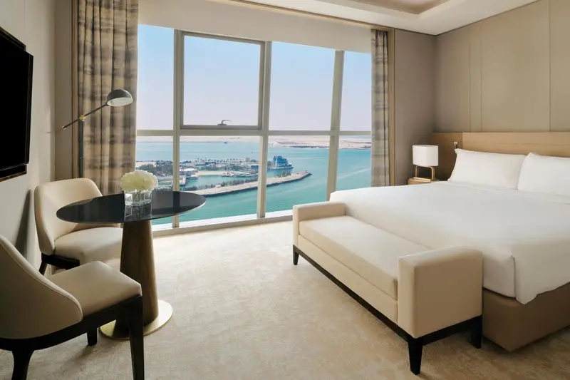 Chambre lumineuse avec un grand lit et une vue sur la mer.