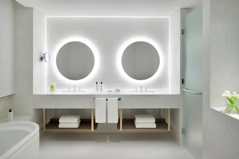 Une salle de bain moderne avec un grand miroir lumineux et un plan vasque double.