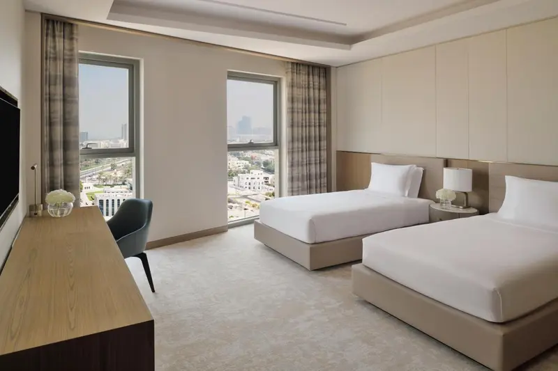 Une chambre lumineuse avec deux lits simples et une vue sur la ville.