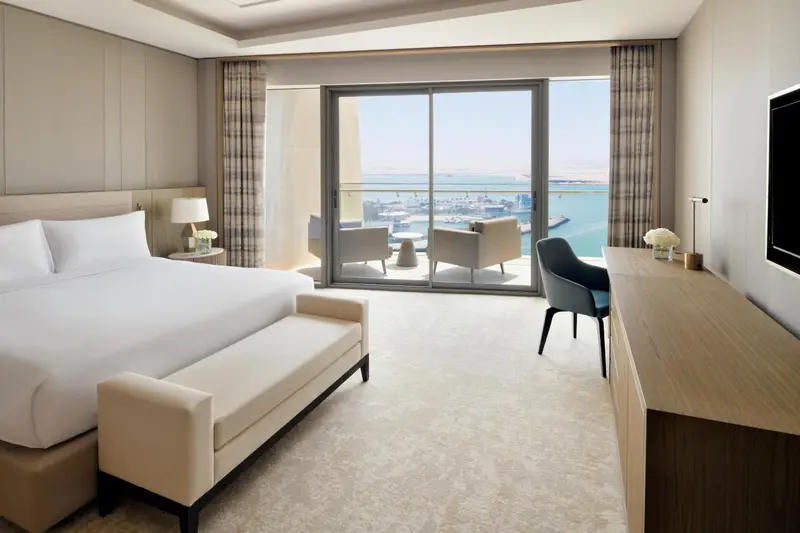 Une chambre lumineuse avec un grand lit et un accès à une terrasse vue sur mer.