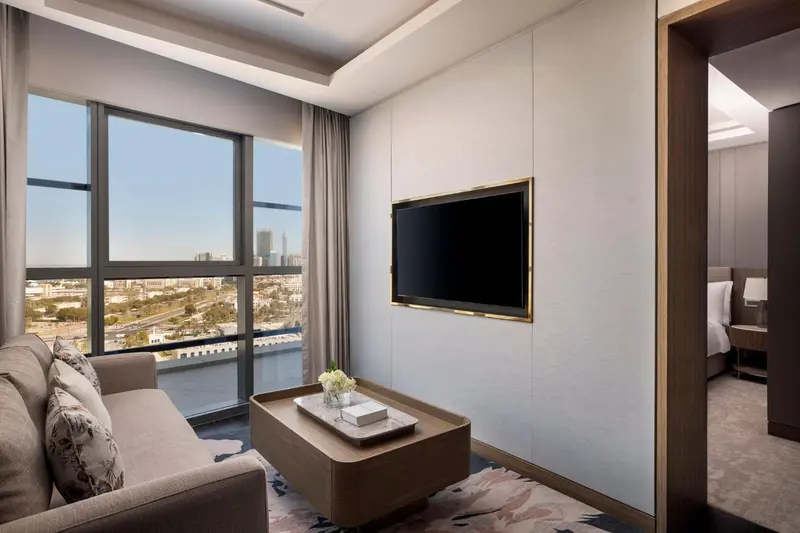 Espace de détente avec canapé face à une grande fenêtre offrant une vue sur la ville.