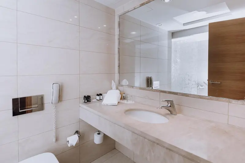 Une salle de bain claire avec un grand miroir et un lavabo en marbre.